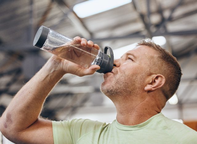 mature man drinking water bottle during workout