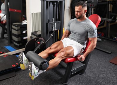 muscular man doing leg extension exercises for bigger legs