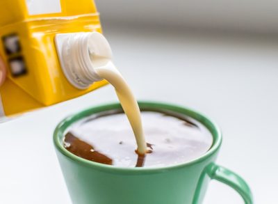adding creamer to cup of coffee