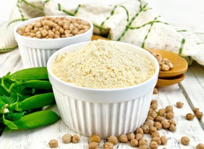 Vegan pea protein powder in white ramekin next to whole pea pod